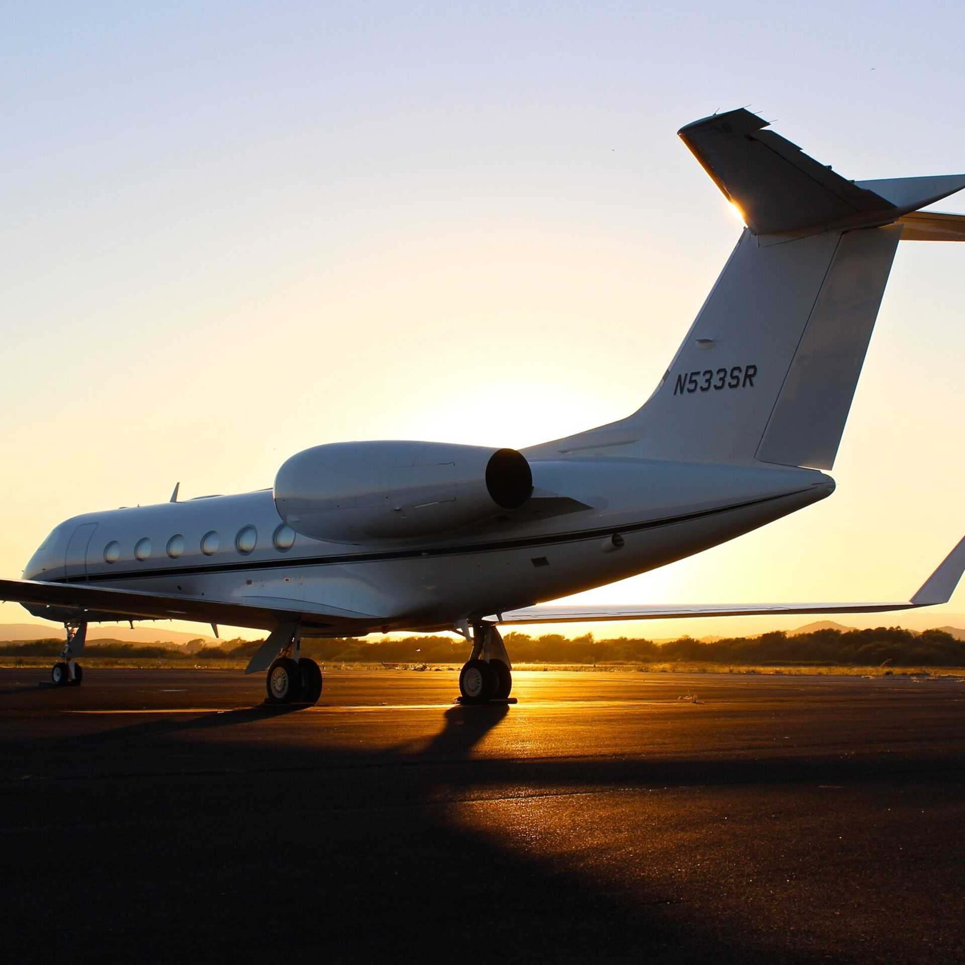 A personal jet on the runway at sunset.