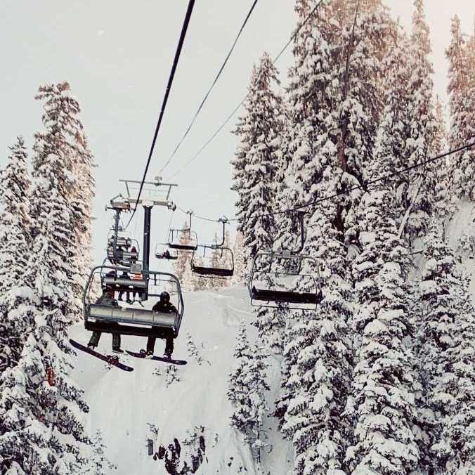 Snowboarders riding a lift at a winter sports resort.